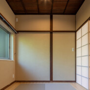 color garden 26 がリノベーションを手掛けた鎌倉浄明寺の家の和室。天井はキッチンと同じ茶色い木で作られ、格子状に組まれている。出入り口は障子を思わせる引き戸。床は壁際がフローリングになっており、中央に琉球畳が4枚置かれている。壁は薄いモスグリーンで、出入り口の反対がわに小さな窓がある。
