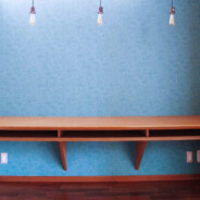 color garden 26 が手掛けた横浜個人邸のワーキングスペース。作り付けの机の壁面はブルーの壁紙が貼られている。天井近くに窓があり、適度な採光がなされている。足元にはコンセントが設置され、PC作業やアイロン掛けなどに便利な場所となっている。
